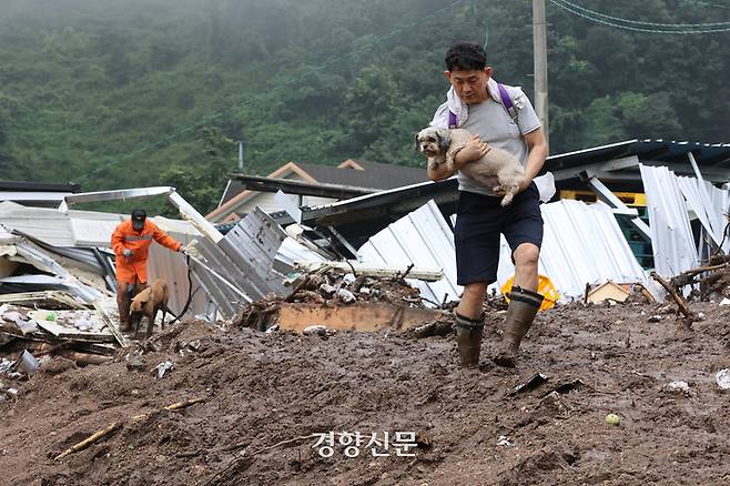 집중호우로 산사태가 발생해 마을 대부분이 매몰된 경북 예천군 효자면 백석리 일대에서 16일 마을 주민의 가족이 부모님이 키우던 반려견과 함께 토사가 덮친 집을 빠져나오고 있다. 조태형 기자