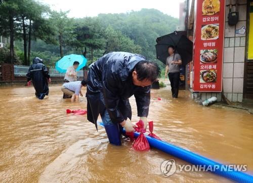 군산 시내 도로에서 물 빼는 공무원과 주민  [독자 제공. 재판매 및 DB 금지]