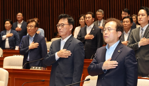 더불어민주당 의원들이 18일 국회에서 열린 의원총회에서 국기에 대한 경례를 하고 있다. [연합뉴스]