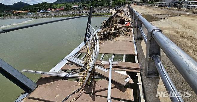 [괴산=뉴시스] 강신욱 기자 = 17일 오후 충북 괴산군 칠성면 수전교 보행로 상판이 침수로 뜯겨져 나가 강물이 훤히 보이고 난간이 엿가락처럼 휘어 있다. 수전교는 지난 15일 괴산댐에서 방류된 물에 침수됐다. 2023.07.17. ksw64@newsis.com