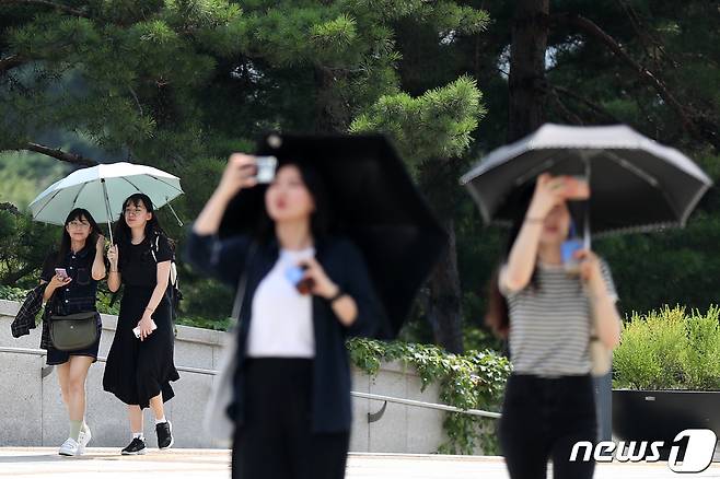 장마전선이 물러간 뒤 서울 지역 낮 최고기온이 33도를 넘어 폭염주의보가 발령된 19일 오후 서울 용산구 국립중앙박물관을 찾은 시민들이 양산을 펼쳐 따가운 햇빛을 피하고 있다. 2023.7.19/뉴스1 ⓒ News1 민경석 기자