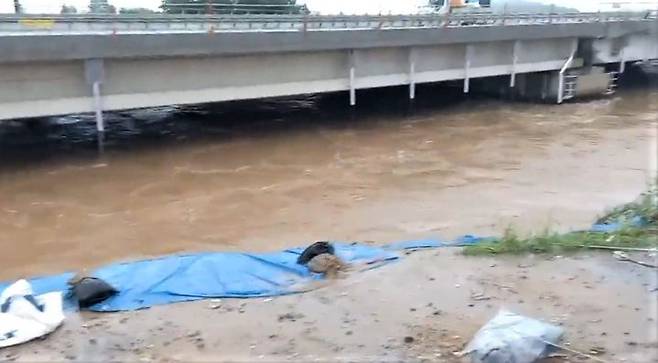[청주=뉴시스] 이병찬 기자 = 행정중심복합도시건설청이 미호교 확장 공사를 위해 축소한 임시 제방이 15일 불어난 강물에 붕괴했다. 이 강물은 300~400m 떨어진 지하차도를 순식간에 집어삼켰다. 방수포가 덮였던 이 임시 제방은 애초 교량 아래를 가로지르는 형태였다.(사진=주민 제공)2023.07.18.photo@newsis.com *재판매 및 DB 금지