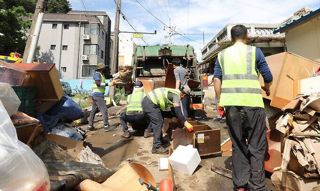 지난 17일 충남 공주시 옥룡동 일대 폭우 침수현장에서 주민들과 자원봉사자들이 물에 젖은 가구 등을 옮기고 있다. 뉴스1