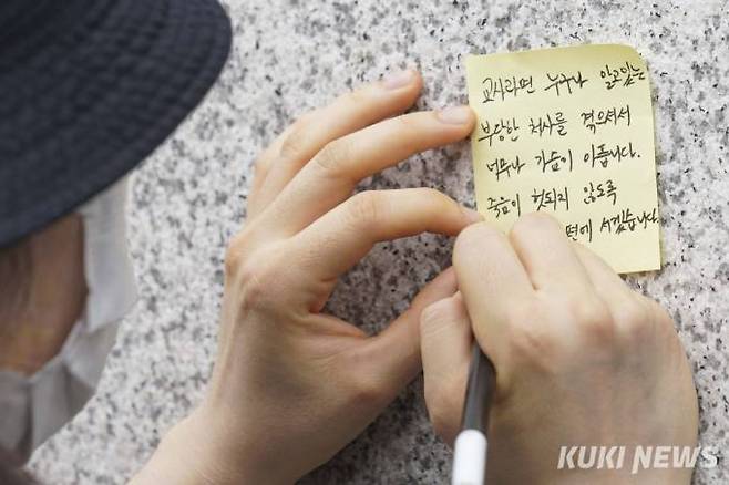 20일 오후 서울 서초구 한 초등학교 담벼락에서 쪽지에 추모 메시지를 적고 있는 시민.   사진=임형택 기자