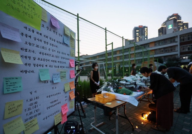 20일 오후 서울 서초구 서이초등학교에 마련된 임시 추모공간에 고인이 된 교사 A씨를 기리는 추모객들의 발길이 이어지고 있다. 임시 추모공간 옆에 21일부터 강남서초교육지원청에 추모공간을 마련한다는 안내문이 게시돼 있다. 연합뉴스.