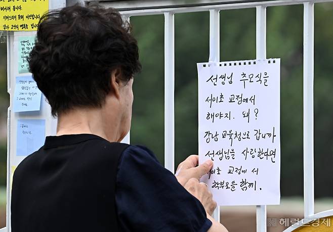 인근 주민이 서이초등학교 정문에 추모식과 관련해 학교와 교육당국을 비난하는 문구가 적힌 메모지를 부착하고 있다. 이 주민은 취재진에 "추모식을 왜 교육청에서 하는지 알 수 없다"며 추모식을 학교에서 하지 않는 것을 두고 비난했다. 임세준 기자