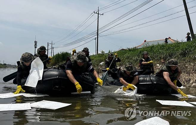 육군 장병들의 따뜻한 손길 (익산=연합뉴스) 20일 7공수특전여단 장병들이 집중호우로 피해를 본 전북 익산시 망성면에서 흡착포를 이용해 일대 하천에 유출된 기름과 부유물을 걷어내고 있다. 2023.7.20 [육군 제35보병사단 제공. 재판매 및 DB 금지] warm@yna.co.kr