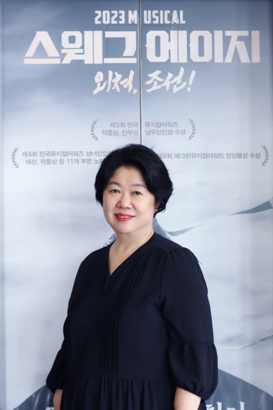 송혜선 PL엔터테인먼트 대표가 홍익대 대학로 아트센터에서 공연 중인 뮤지컬 '스웨그에이지: 외쳐, 조선!' 포스터 앞에서 포즈를 취하고 있다. PL엔터테인먼트 제공