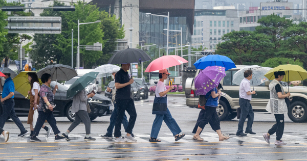 올여름 장마가 시작된 지난달 26일 동래구 도시철도 1호선 동래역 앞 교차로에서 시민들이 빗길 속 출근길에 오르고 있다. 국제신문DB