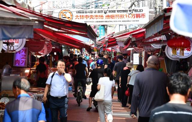 이주민들은 여전히 한국사회에서 크고 작은 차별의 시선을 느낀다고 말했다. 장을 보러 나온 시민들이 지난 24일 서울 영등포구 대림 중앙시장에서 한국어와 중국어가 함께 쓰인 금연 홍보 현수막 아래를 지나고 있다. 권현구 기자