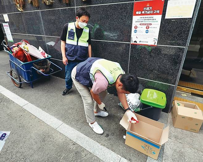 순찰에 나선 자양1동 주민센터 직원들이 반지하 가구의 물막이판을 점검하고 무단투기 쓰레기를 정리하고 있다.