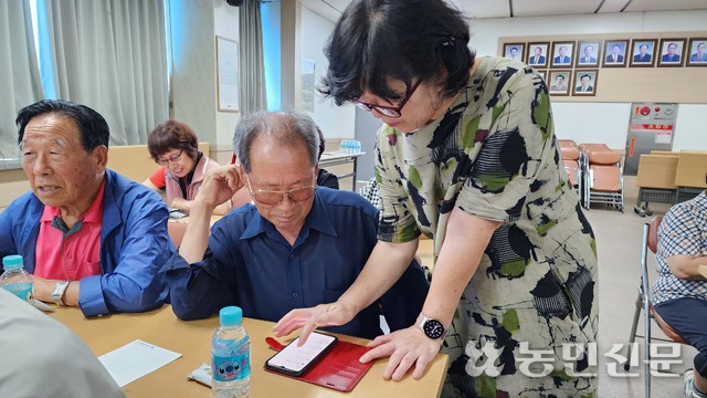 25일 동부여농협에서 열린 어르신 스마트폰 활용교육에서 강사 이인희씨(오른쪽)가 한 어르신을 지도하고 있다.