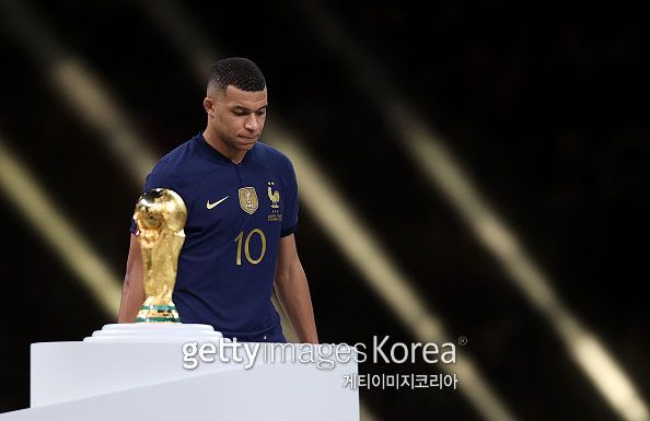 LUSAIL CITY, QATAR - DECEMBER 18: Kylian Mbappe of France walks past the FIFA World Cup trophy as he looks dejected following his teams loss in the FIFA World Cup Qatar 2022 Final match between Argentina and France at Lusail Stadium on December 18, 2022 in Lusail City, Qatar. (Photo by Julian Finney/Getty Images)