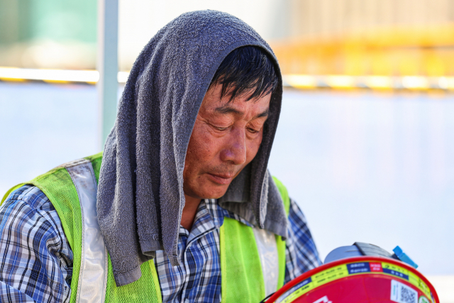 서울 한낮 기온이 35도까지 치솟으며 무더운 날씨를 이어간 1일 오후 서울 시내 한 공사 현장에서 건설 노동자의 머리에 얹은 수건이 땀으로 젖어 있다. 연합뉴스