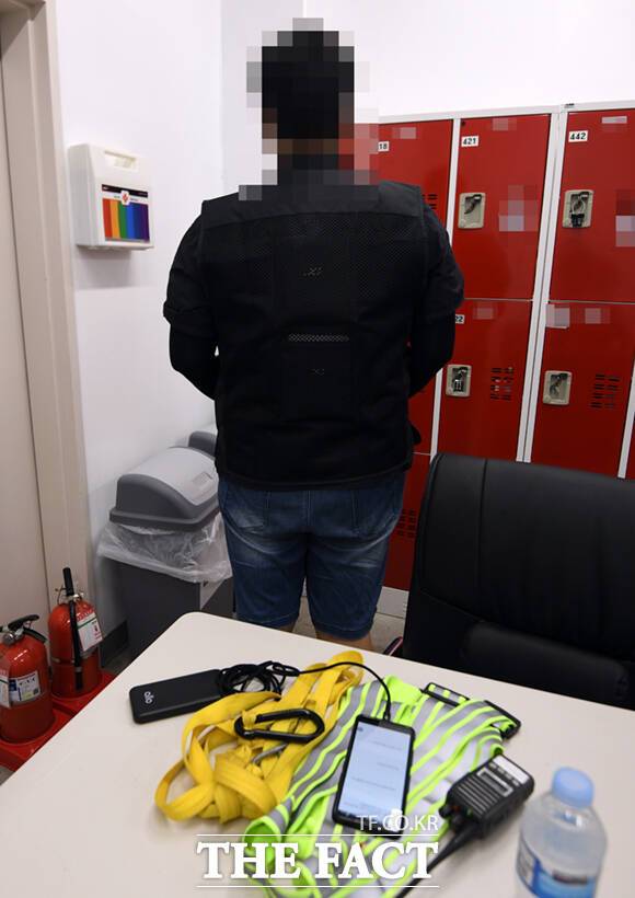 휴식을 마친 한 근로자가 얼음 조끼를 착용하고 있다. 테이블에 카트를 끌기 위한 스트랩과 무전기, 생수 등이 보이고 있다.