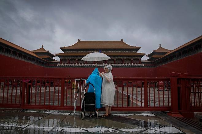 30일 태풍 '독수리'가 몰고 온 폭우가 베이징을 강타한 가운데 닫힌 자금성 입구 앞에 관광객들이 서 있다.  /AP 연합뉴스