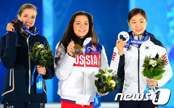 '피겨여왕' 김연아가 22일(한국 시간) 러시아 소치 해안클러스터의 올림픽 파크 내 메달 프라자에서 열린 피겨 여자 싱글 시상식에서 은메달을 목에 걸고 환하게 미소짓고 있다. 1위 아델리나 소트니코바(러시아),2위 김연아(대한민국),3위 카롤리나 코스트너(이탈리아)2014.2.22/뉴스1