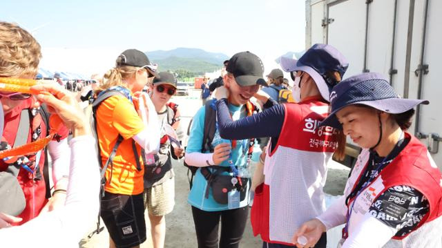 희망브리지 전국재해구호협회 관계자들이 5일 2023 새만금 세계잼버리대회 참석자들을 위해 쿨스카프를 나눠주고 있다. 포스코와 LG는 쿨스카프 2만5,000장을, LG는 얼음물을 제공할 냉동차량 여섯 대, 하이트진로는 생수 10만 병, 동아오츠카는 박카스 5,000병을 전했다. 현대차그룹과 롯데의 후원으로 제작된 심신회복차량도 투입됐다. 희망브리지 제공