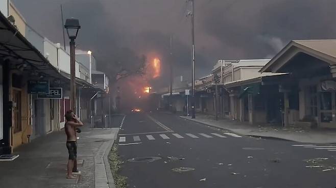 대형 산불이 발생한 미국 하와이주 마우이섬 라하이나의 해안에서 8일 주민이 불길과 검은 연기가 치솟고 있는 모습을 보고 있다. 로이터 연합뉴스