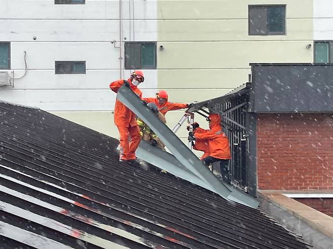 8.10.(목) 오전, 대구 동구 신암동에서 강풍으로 건물 지붕 함석판이 떨어지려는 상황으로 출동한 소방대원들이 안전조치를 하고 있다.