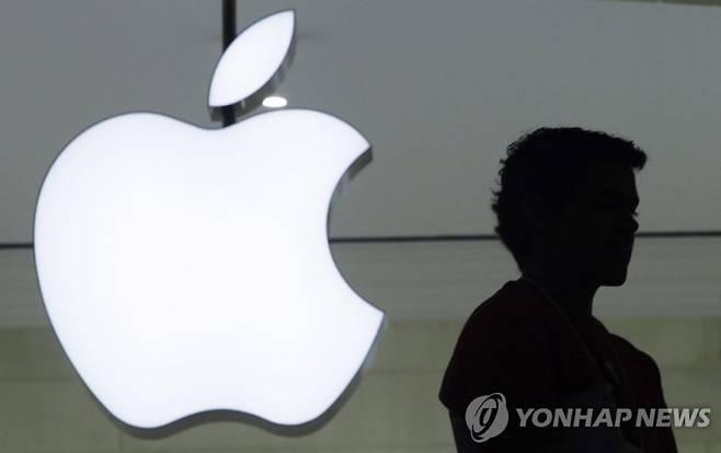 FILE - In this Dec. 7, 2011 file photo, a person stands near the Apple logo at the company's new store in Grand Central Terminal in New York. Amazon and Apple were fined a total of 194 million euros ($218 million) Tuesday for colluding to box out competitors by favoring sales of Apple products directly from the online retail giant, Spain’s antitrust watchdog said. (AP Photo/Mark Lennihan, File) DEC. 7 2011 PHOTO