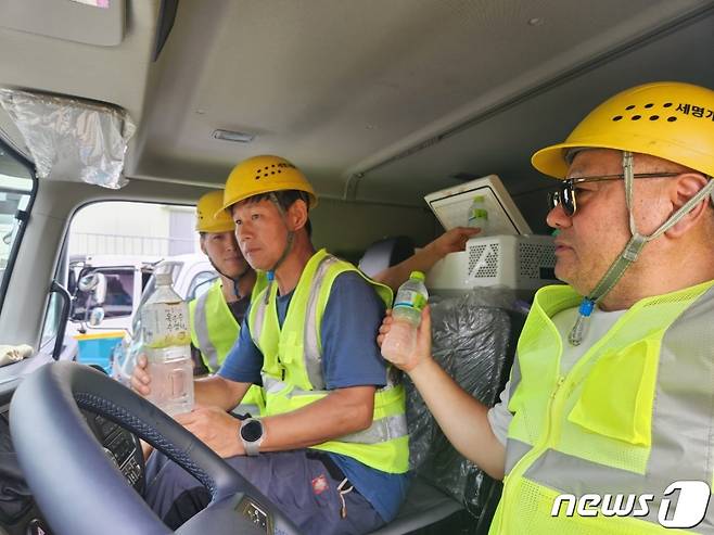 안양시 폐기물 수거 및 운반 근로자들이 차량에 설치된 휴대용 냉장고에서 음료를 꺼내고 있다.(안양시 제공)