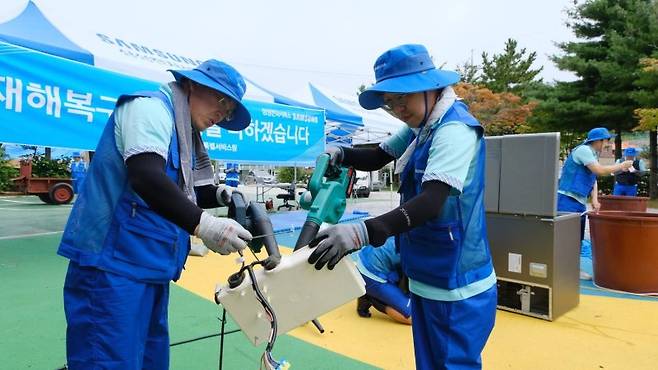 삼성전자서비스 직원들이 14일 강원도 고성군 거진청소년문화의집에 이동식 서비스센터를 설치하고 '수해 복구 특별서비스'를 실시하고 있다. 삼성전자서비스 제공