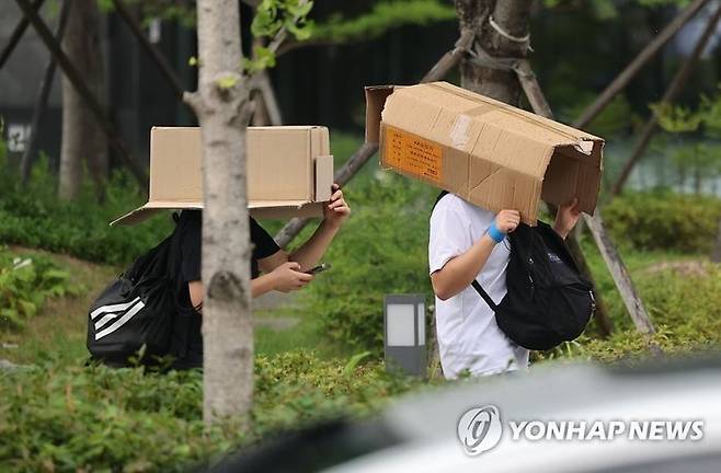 서울에 소나기가 내린 6일 오후 서울 새문안로에서 학생들이 박스로 머리를 가린 채 걸어가고 있다. ⓒ연합뉴스