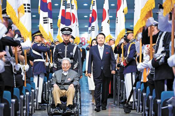 President Yoon Suk Yeol, right, enters with 100-year-old independence fighter Oh Seong-gyu, pushed in a wheelchair by a military officer, for the 78th Liberation Day ceremony at a Ewha Womans University auditorium in Seodaemun District, central Seoul on Tuesday. [PRESIDENTIAL OFFICE]