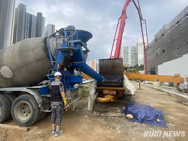 레미콘 차량이 콘크리트를 펌프차량에 옮기고 있다. 사진에 보이는 붉은 배관길이는 5~60m다. 레미콘이 배관을 타고 작업 현장까지 운반된다.&nbsp; 사진=송금종 기자&nbsp;