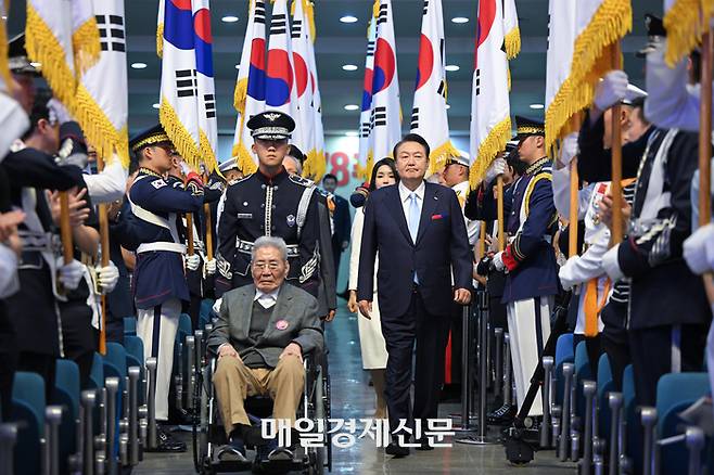 윤석열 대통령이 제78주년 광복절 경축식에 참석하기 위해 15일 서울 서대문구 이화여자대학교 대강당에 부인 김건희 여사(윤 대통령 뒤편), 오성규 애국지사(앞쪽 휠체어 탑승)와 함께 입장하고 있다. <사진=이승환 기자>