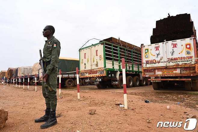 니제르의 수도 니아메에서 한 경찰관이 부르키나파소에서 도착한 음식을 실은 300대 트럭의 일부를 지키며 서 있다. 2023.08.21.ⓒ AFP=뉴스1