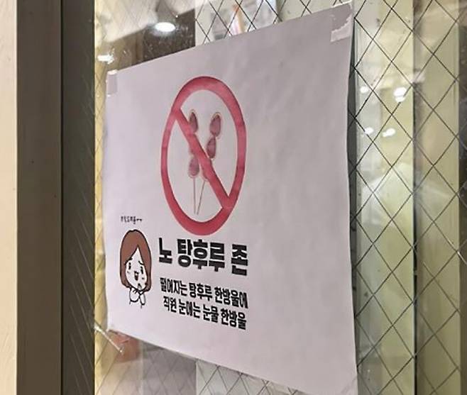 21일 서울 홍대 인근 한 점포 앞에 탕후루 나무꼬치가 수북하게 꽂혀 있다(위 사진). 탕후루로 인한 나무꼬치와 종이컵 쓰레기가 문제가 되자 한 업소에서 탕후루를 들고 들어올 수 없다는 안내문을 입구에 붙여놓고 있다. 강은 기자·SNS 갈무리
