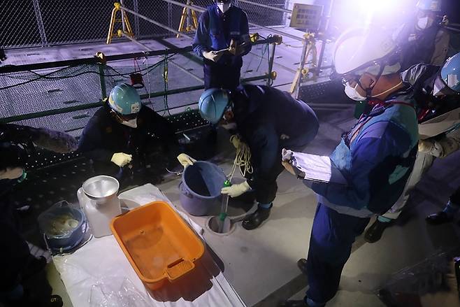 일본 정부가 이르면 오는 24일부터 후쿠시마 제1원자력발전소 오염수(일본 정부 명칭 ‘처리수’)를 해양에 방류하겠다고 발표한 가운데 22일 준비 작업에 착수한 도쿄전력 작업자들이 표본을 채취하고 있다. | AFP연합뉴스