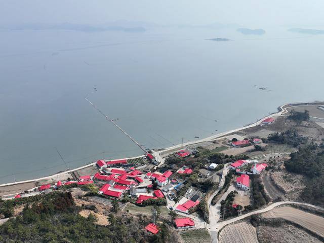 하늘에서 본 옥도의 큰 마을. 집집마다 섬의 상징색인 빨강으로 칠한 지붕과 바다 위로 닦여 있는 노둣길이 눈에 띈다. 신안군 제공