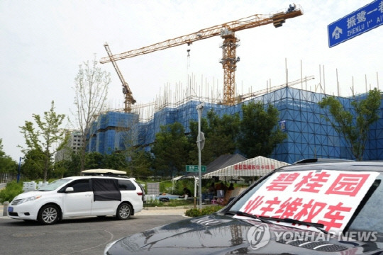 지난 8월 17일 중국 대형 부동산 업체 비구이위안(碧桂園·컨트리가든)의 베이징 외곽 공사 현장 근처 차량에 "비구이위안 주택 구매자 권리 보호"라는 문구가 적힌 팻말이 놓여 있는 모습.     연합뉴스