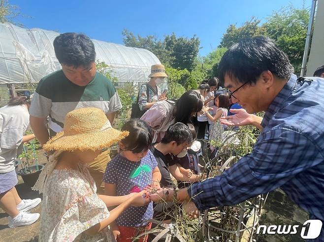 울산과학관 들꽃학습원에서 꼬리명주나비 애벌레는 관찰하는 시민들. (울산과학관 제공)