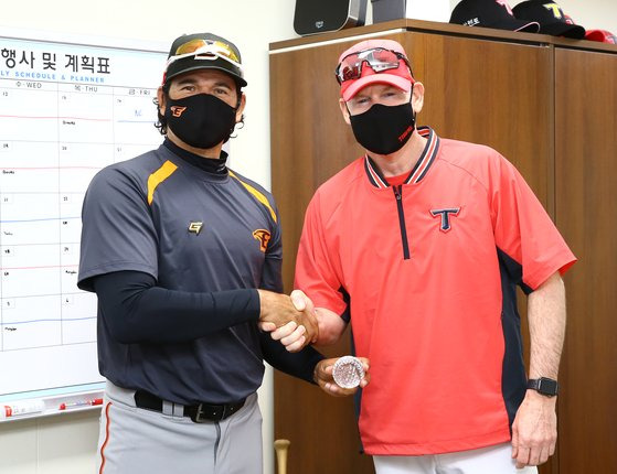 KIA 윌리엄스 감독이 27일 광주-기아챔피언스필드에서 열리는 2021 KBO 프로야구 한화와의 경기에 앞서 수베로 감독에게 선물로 크리스털 야구공을 전달하며 악수를 하고 있다. 사진=연합뉴스 제공