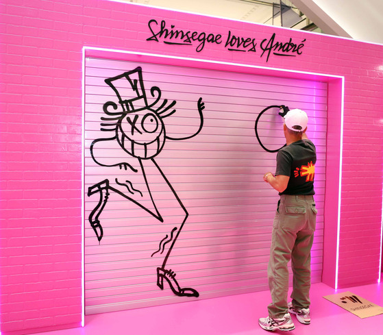 Andre Saraiva, a Swedish-French graffiti artist, paints on a wall during a live drawing show hosted by Shinsegae Department Store at its Gangnam branch in southern Seoul on Monday. [SHINSEGAE DEPARTMENT STORE]