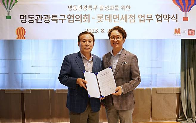 지난 28일 서울 중구 롯데면세점 명동본점에서 열린 '명동 지역 관광 활성화를 위한 업무협약' 체결식에서 김병희 명동관광특구협의회장(왼쪽)과 김주남 롯데면세점 대표이사가 기념촬영을 하고 있다. 롯데면세점 제공