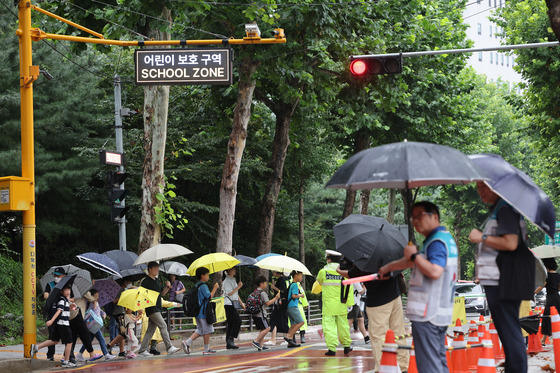 Children cross the road on their way to school in Yangcheon District, western Seoul, at the beginning of the academic term on Monday. [YONHAP]