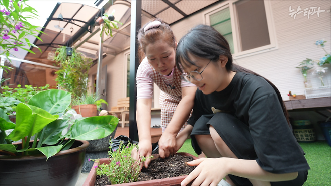 ▲ 집 앞마당에서 채송화를 심고 있는 하늘이(2007년생)와 엄마&nbsp;