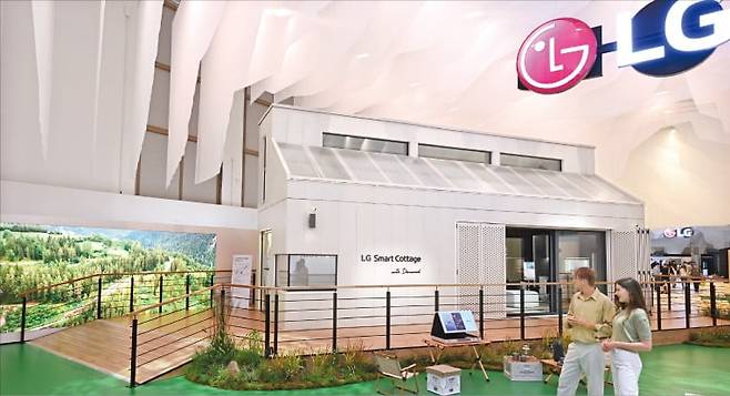 LG전자 모델이 31일 IFA 전시장 내 ‘LG 지속가능한 마을’ 입구에서 냉난방 시스템과 프리미엄 가전 등을 갖춘 소형 모듈러 주택 ‘LG 스마트코티지’의 특징을 설명하고 있다.  /LG전자 제공