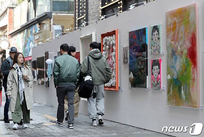 9일 서울 용산구 이태원 세계음식문화거리에서 열린 거리전시회 '헤이, 이태원'을 찾은 시민과 외국인 관광객이 전시된 작품을 살펴보고 있다. 2023.4.9/뉴스1 ⓒ News1 박세연 기자