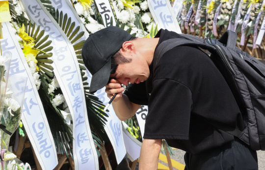 2일 오전 서울 양천구 소재 초등학교 앞에 마련된 숨진 교사 A씨의 추모공간에서 한 추모객이 헌화한 뒤 오열하고 있다. 지난 1일 경찰과 서울시교육청에 따르면 지난달 31일 오후 7시께 고양시 덕양구의 한 아파트에서 14년차 교사 A(38)씨가 추락해 숨졌다. A씨는 서울 양천구의 S초등학교에서 6학년 담임을 맡았으며, 전날까지 질병 휴직 중이었다. 연합뉴스