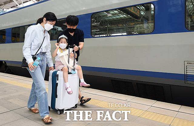 엄마아빠가 끌어주는 캐리어에 올라 손을 흔드는 어린이. /이새롬 기자