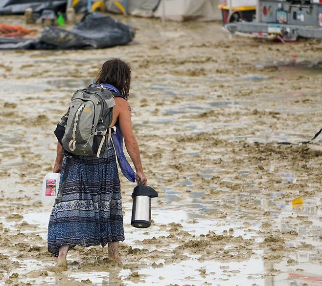 2일(현지시각) 폭우로 진흙탕이 된 미국 네바다주 블랙록 사막의 '버닝맨'(Burning Man) 축제 현장을 한 참가자가 지나고 있다. /로이터 연합뉴스