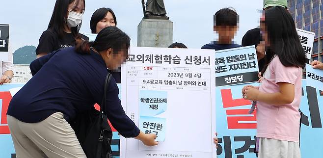 마음은 함께 4일 오전 서울 광화문광장 이순신 장군 동상 앞에서 진행된 ‘공교육 멈춤의 날’ 지지 기자회견에서 학생과 학부모가 현장체험학습판에 표어를 붙이는 퍼포먼스를 하고 있다. 연합뉴스