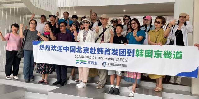 지난달 24일 경기 파주시 탄현면 헤이리 예술마을을 찾은 중국인 관광객 31명이 주황색 깃발을 든 여행사 직원을 따라 아트센터 '화이트블럭'을 관람한 후 기념촬영을 하고 있다. 연합뉴스