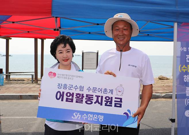 Sh수협은행(은행장 강신숙)은 지난 4일, 전남 장흥 수문해수욕장 일대에서 수협중앙회(회장 노동진)와 공동으로 '해안가 환경정화 플로깅' 캠페인을 펼쳤다. 사진은 수협은행 강신숙 은행장(왼쪽)이 장흥군수협 수문어촌계 김삼식 계장에게 어업활동지원금을 전달하고 기념촬영을 하는 모습.